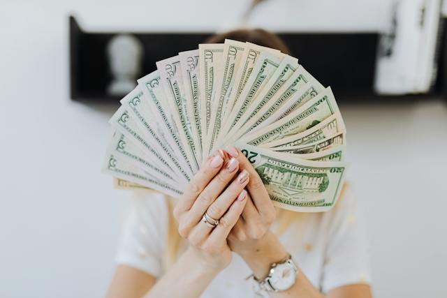 A lady holding dollars spread out like a deck of cards.