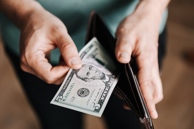 A man pulling out cash dollars from wallet.