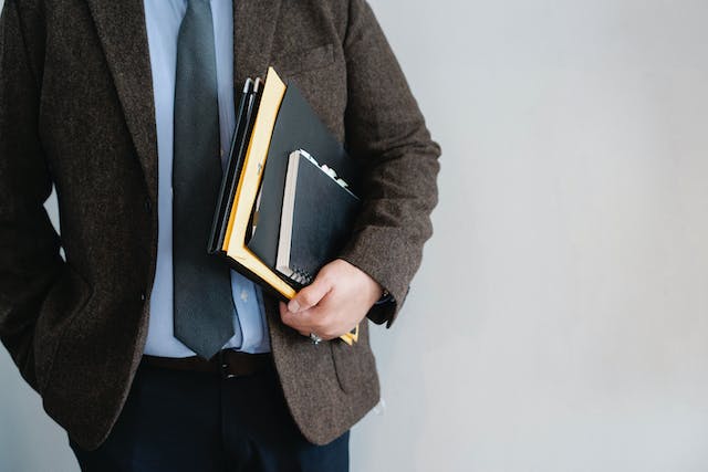 A well dressed man holding files.