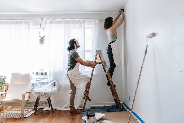 A couple about to paint a white dry wall.