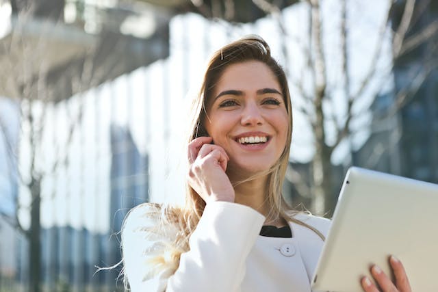 A lady with her mobile phone on her ear, while smiling.