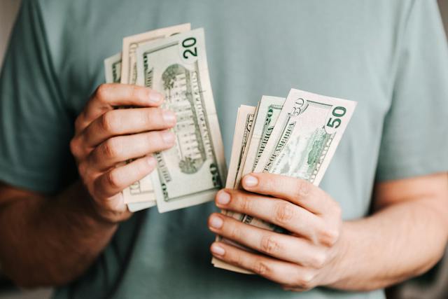 A man holding cash in 2 hands.