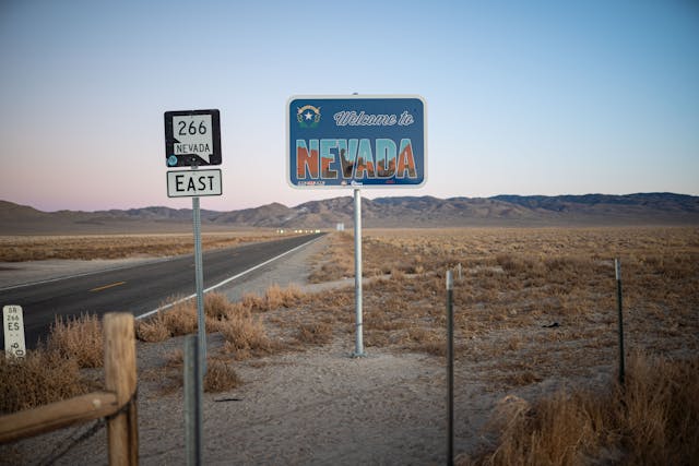 A highway on a desert, with a Nevada sign.