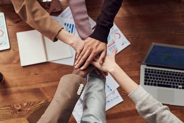 A team have there hands in a circle.