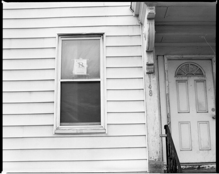 A house with a foreclosure sign hanging on the window.