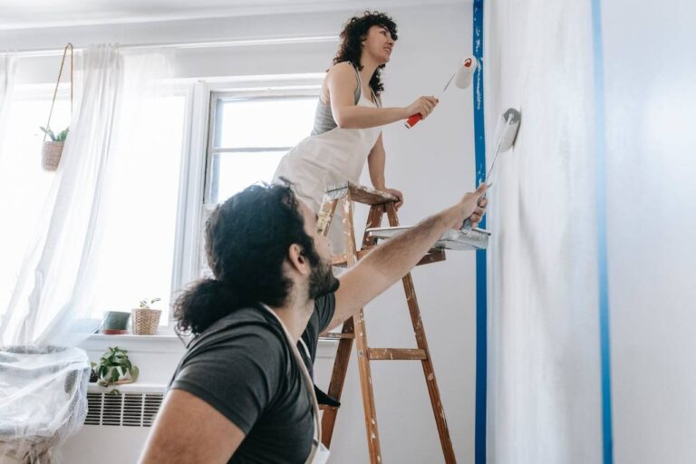 2 people painting a room wall.