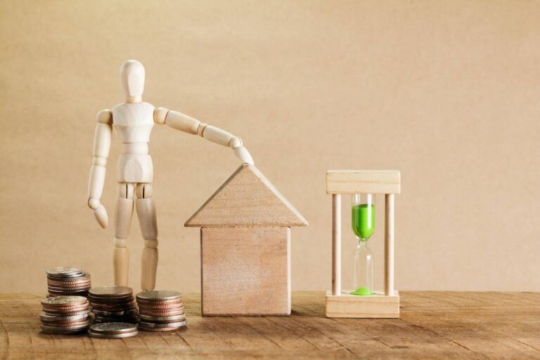 Wooden block figure next to coins.