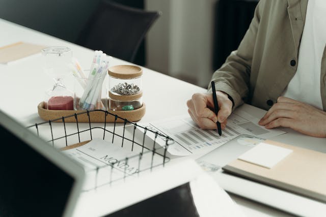 Person holding a pen over some paper.